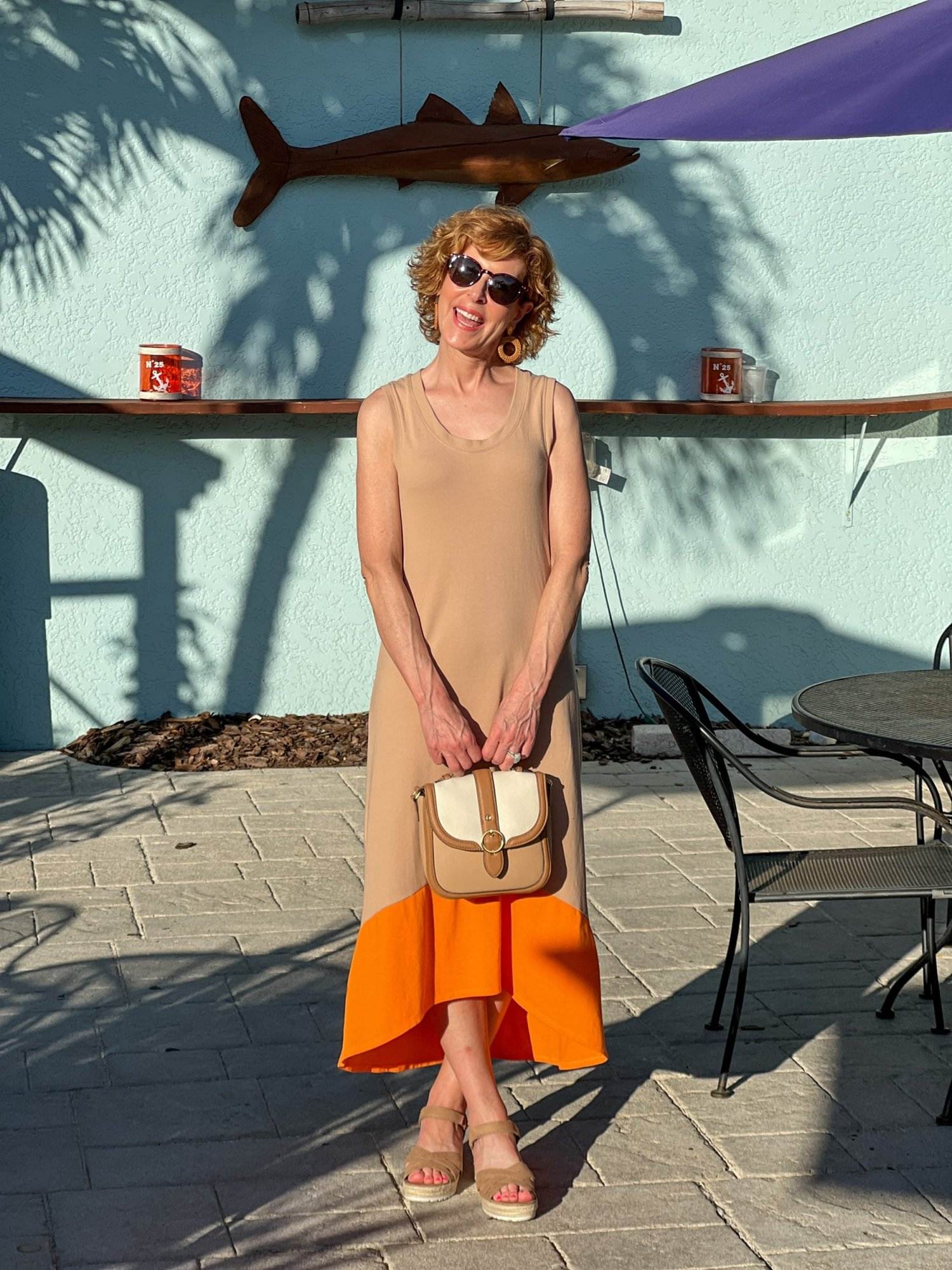 woman over 50 standing on restaurant patio wearing Pique Knit Dress with High Low Hem and demi wedge heels carrying Dana Flap Top Handle Crossbody bag