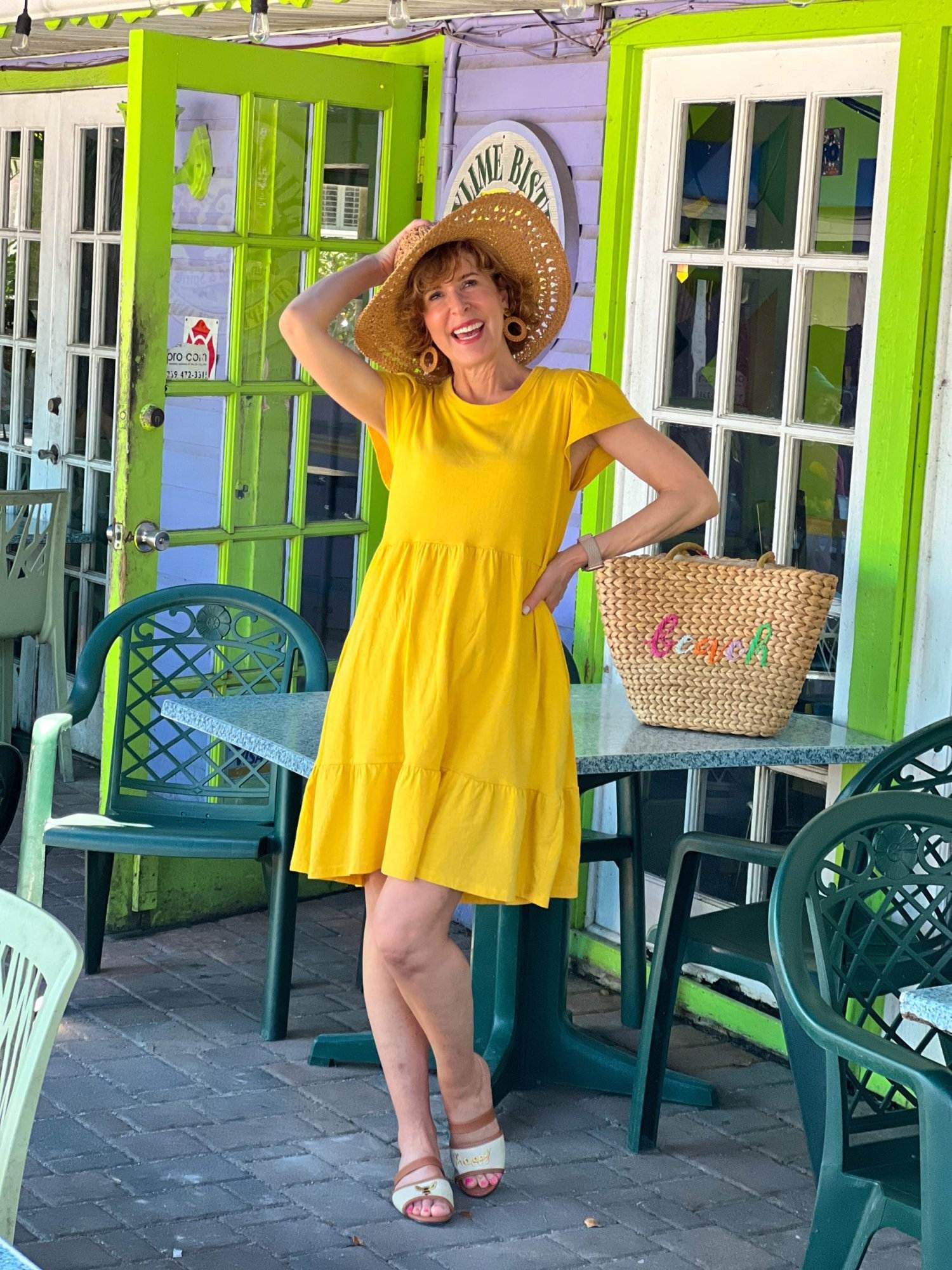 woman over 50 posing at the key lime bistro on captiva island wearing Walmart yellow tiered dress and straw hat