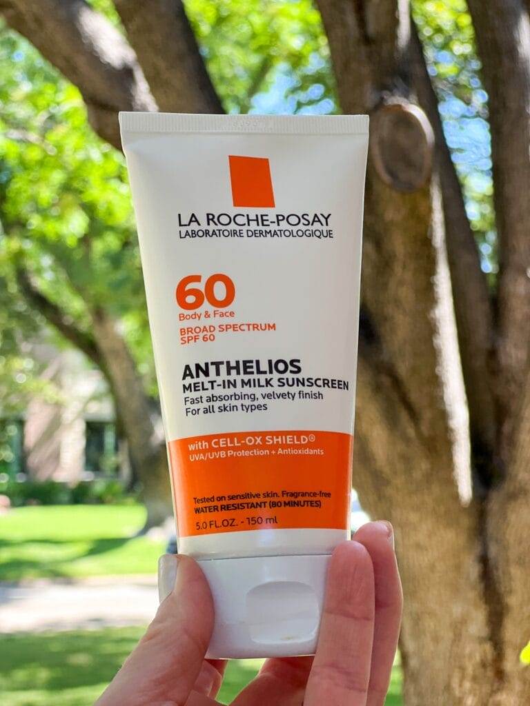 woman's hand holding anthelios melt in milk sunscreen