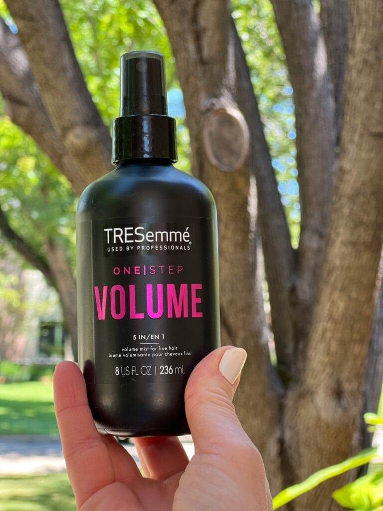 woman's hand holding tresemme one step volume spray