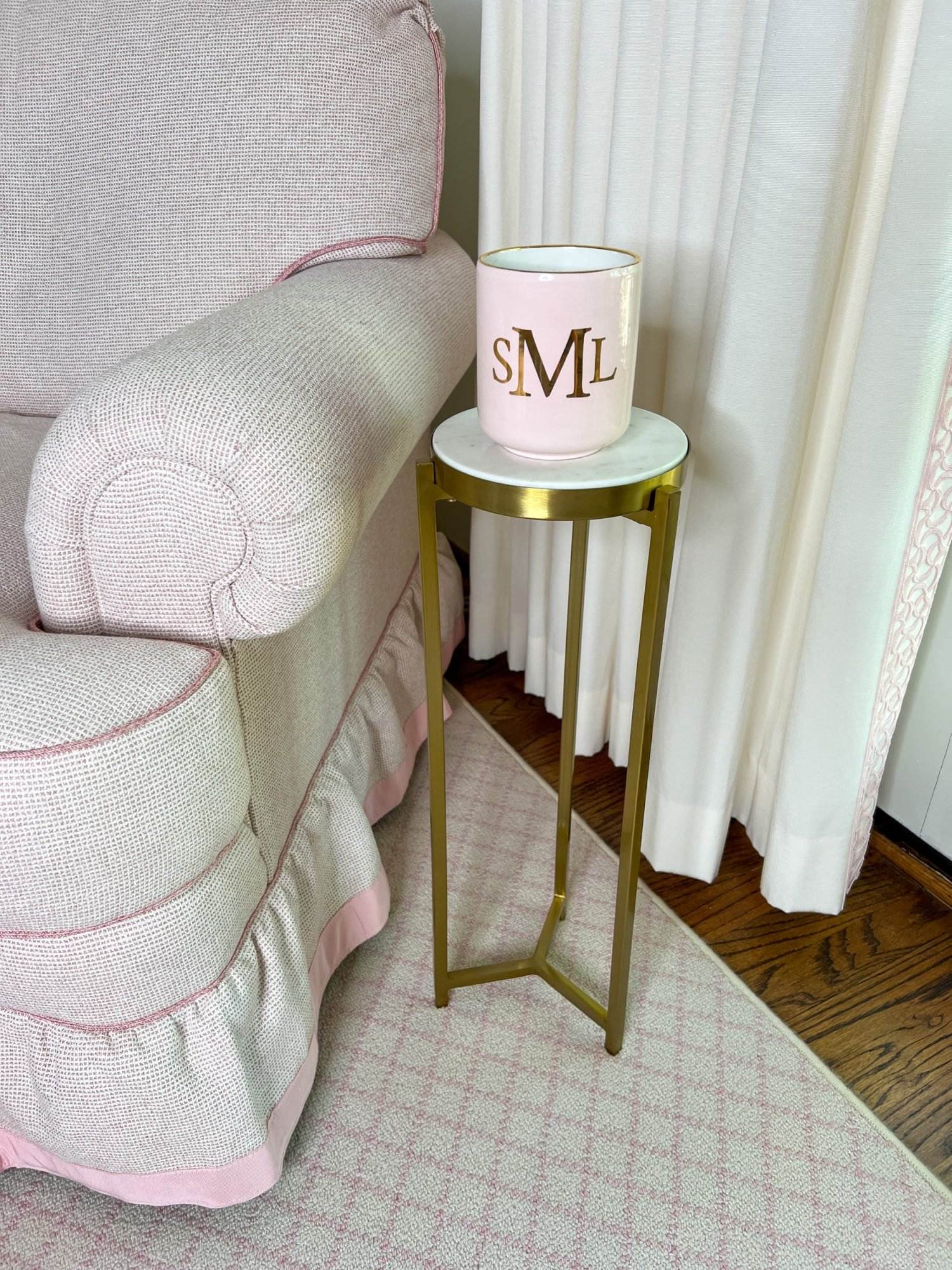 pink monogrammed candle sitting on a martini table beside a pale pink chair