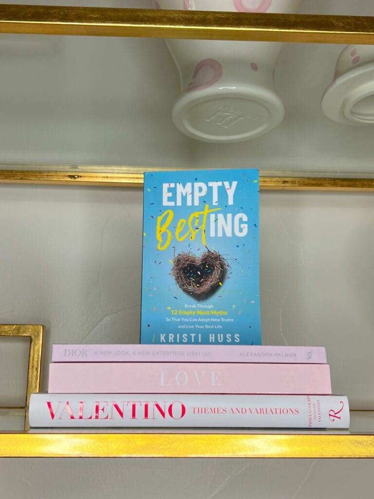 pink coffee table book and empty besting book on glass and brass shelf