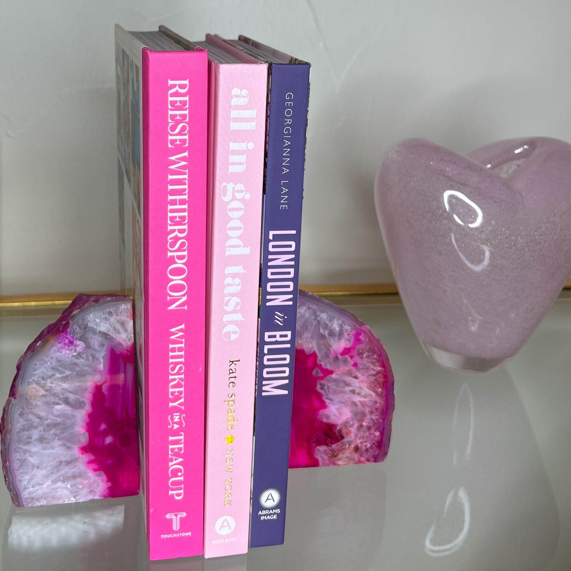 coffee table books with pink geode bookends on a glass shelf