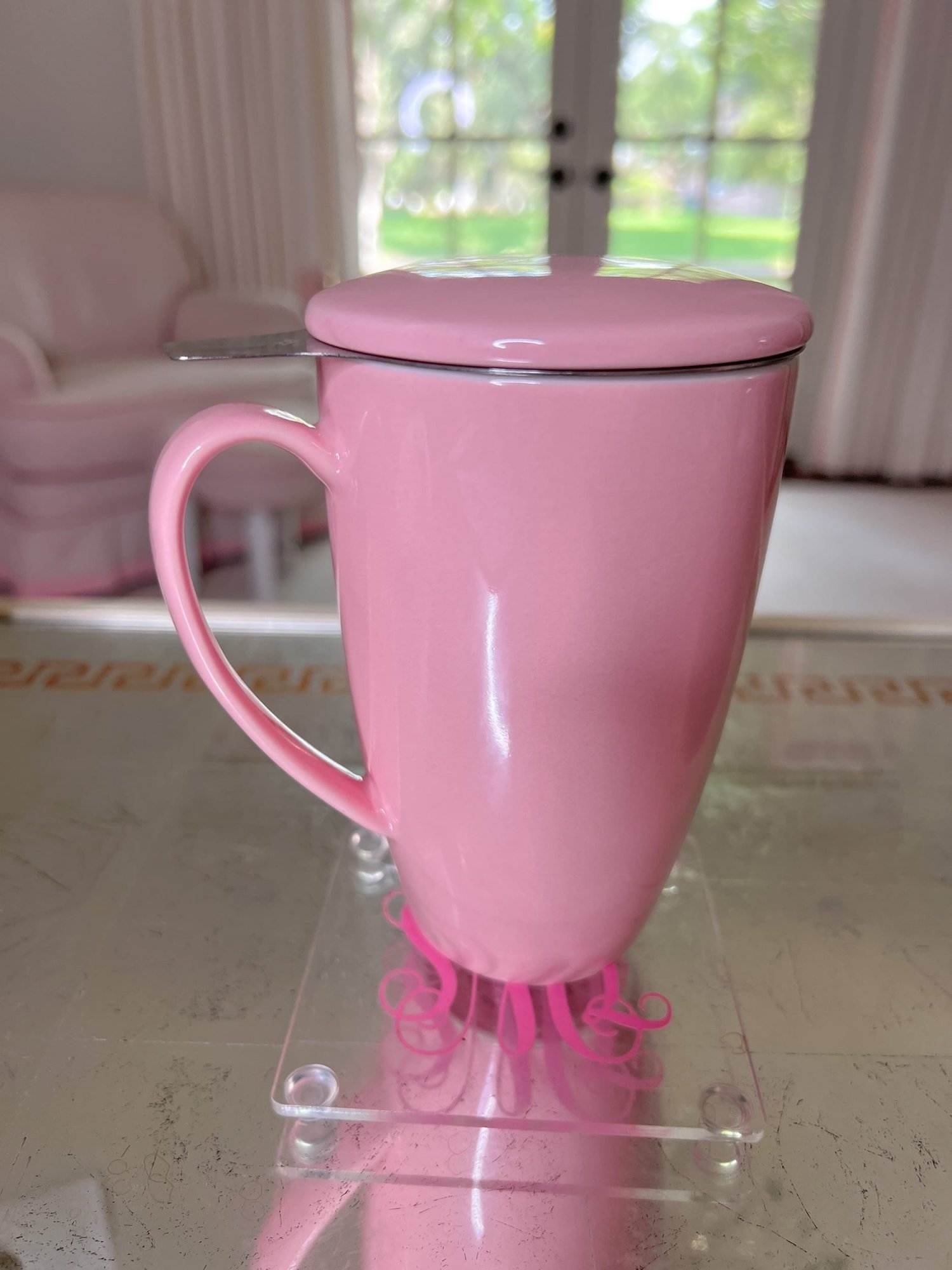 pink coffee mug with lid sitting on acrylic coaster