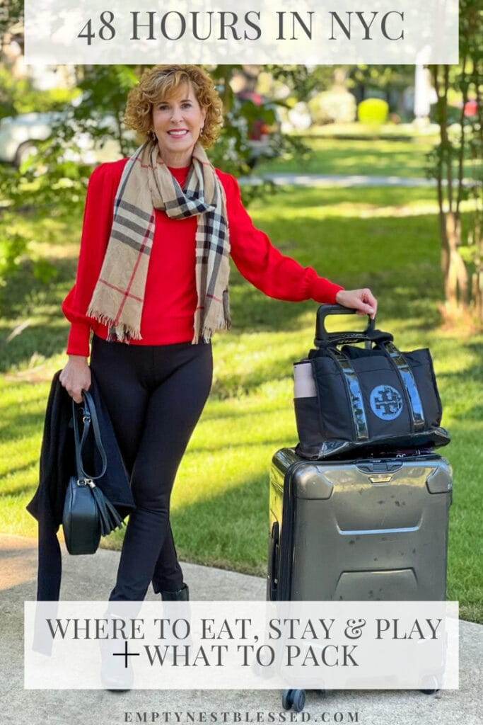 pinterest pin about what to do on a 48 hour trip to nyc featuring photo of a woman over 50 standing on driveway going on Nyc trip wearing spanx black perfect pants, black booties, red cashmere sweater, burberry scarf with suitcase and tory burch tote