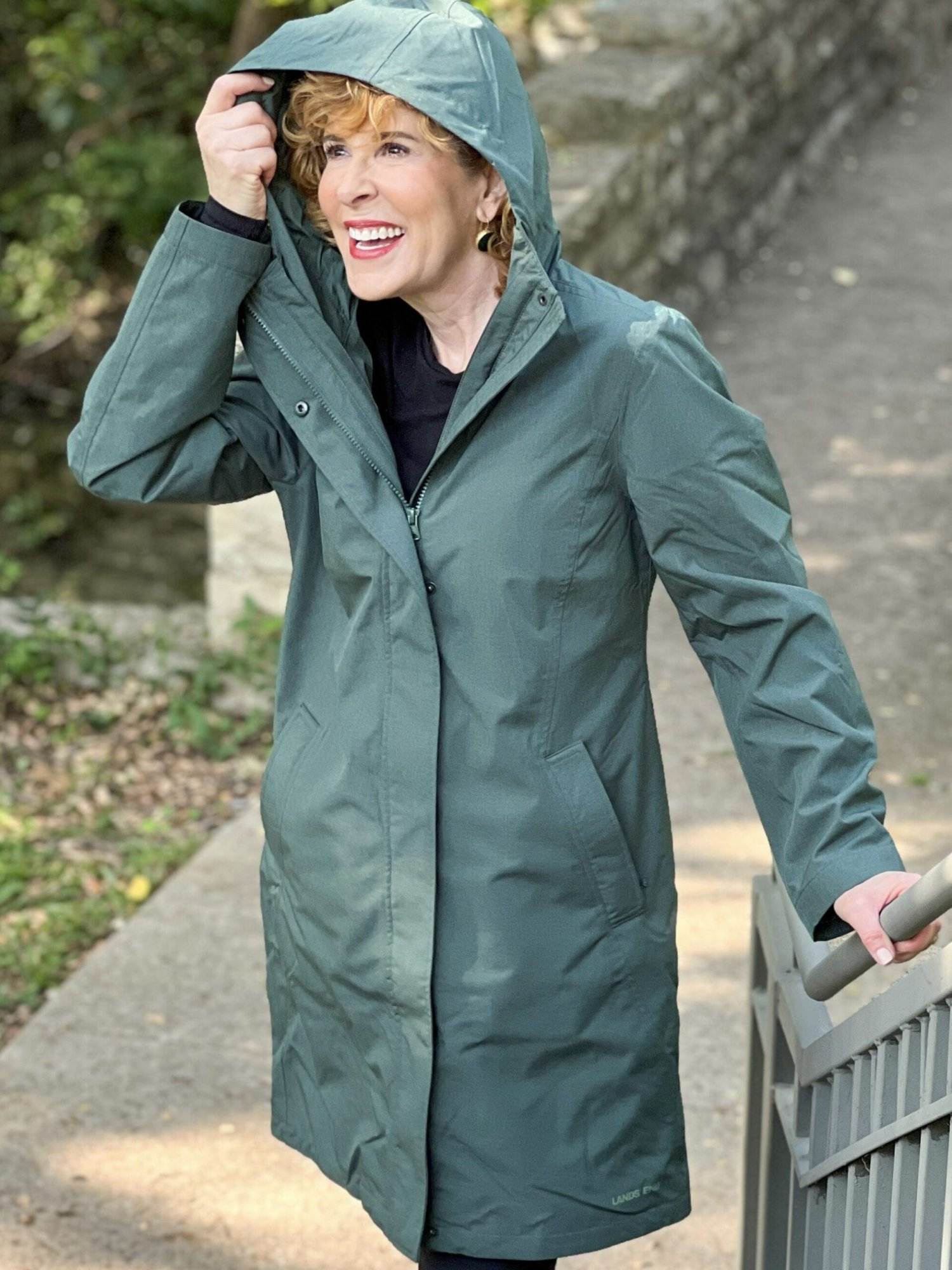 woman wearing green land's end Women's Insulated 3 in 1 Primaloft Parka – outer rain coat part - and black leggings standing by a staircase in the park