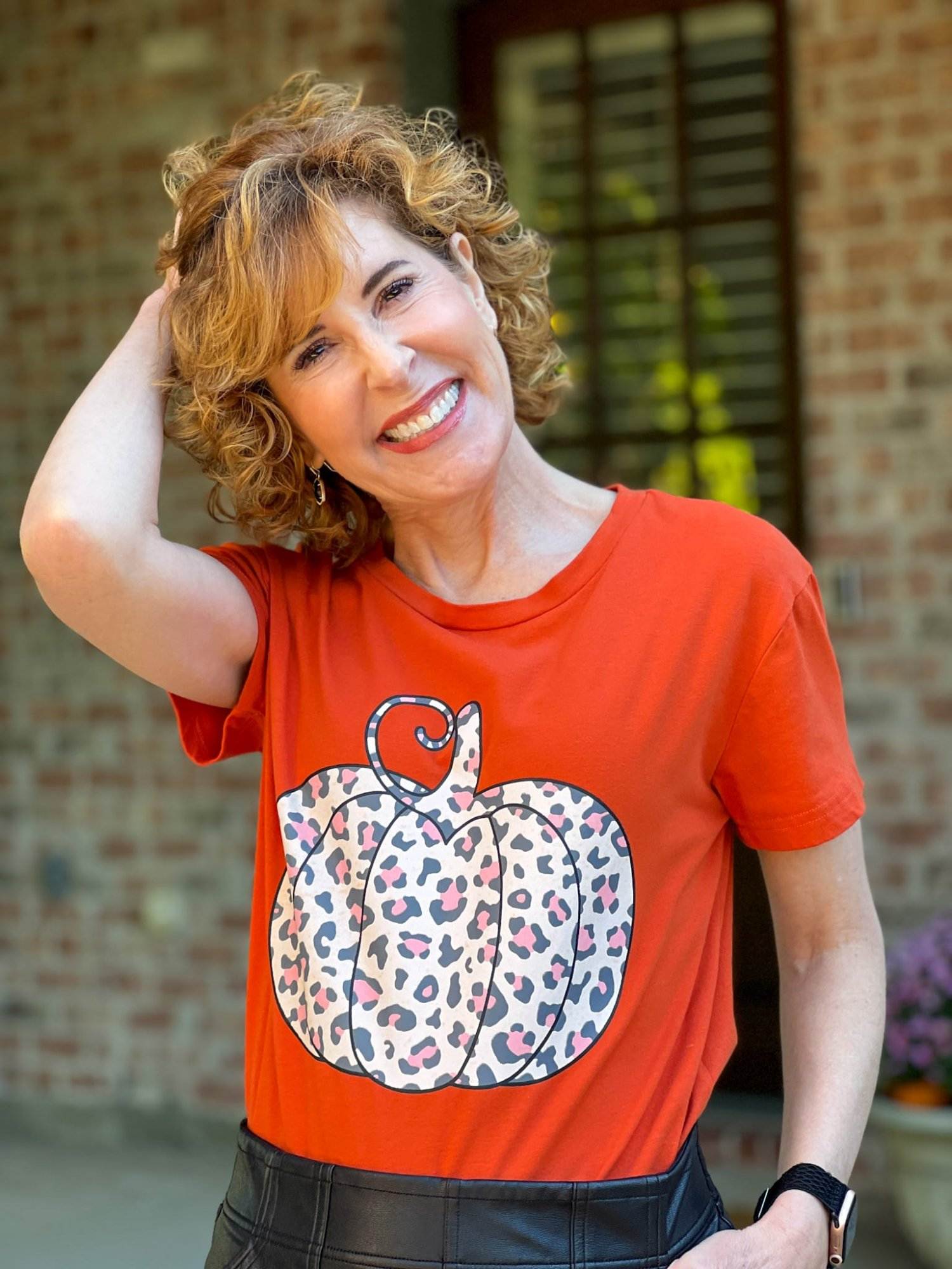 woman standing by her back door wearing a pumpkin tee