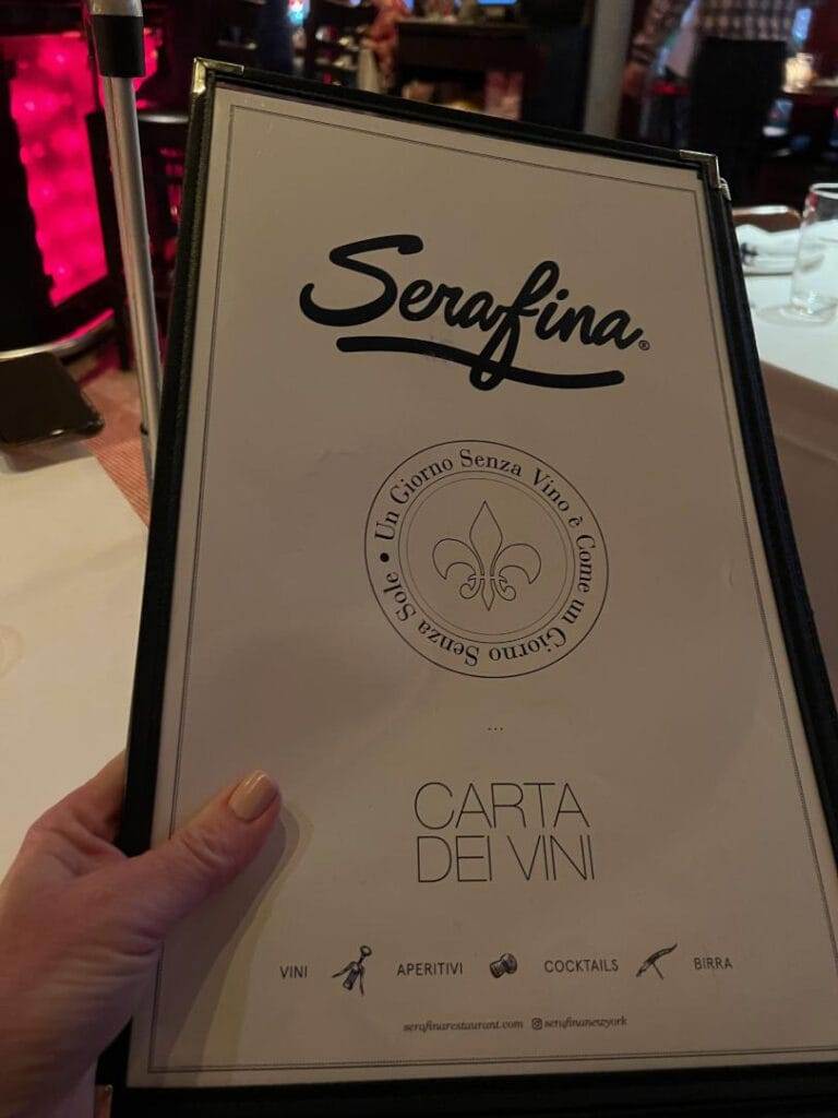 woman's hand holding up a menu from serafina restaurant in nyc