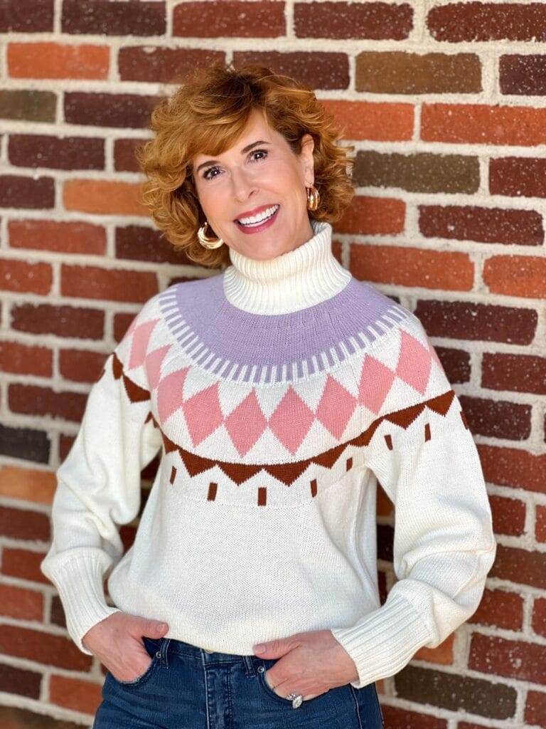 Woman over 50 standing by a brick wall wearing Free Assembly Women's Fair Isle Sweater