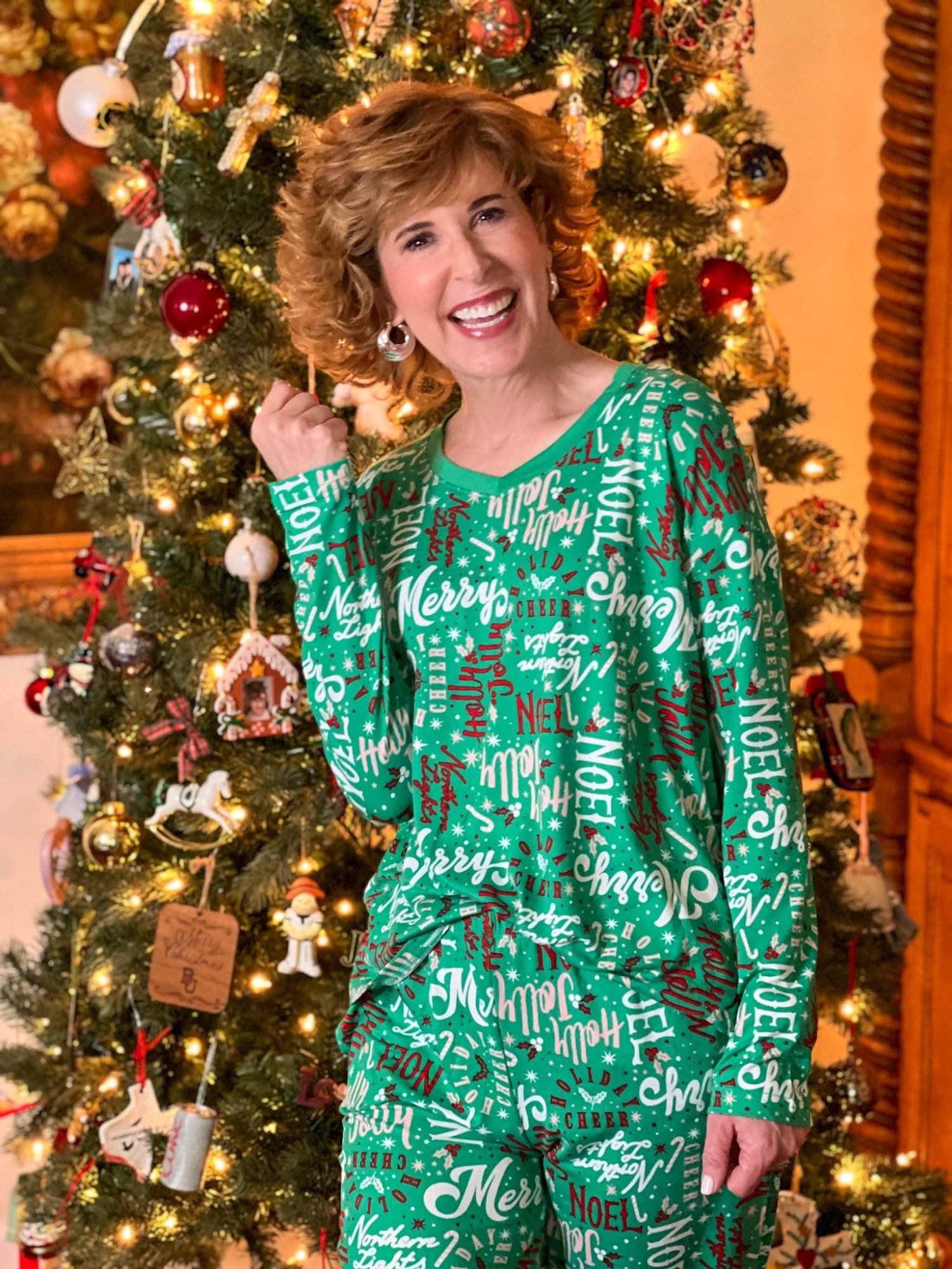 woman over 50 in front of a christmas tree wearing walmart's joyspun holiday pajamas