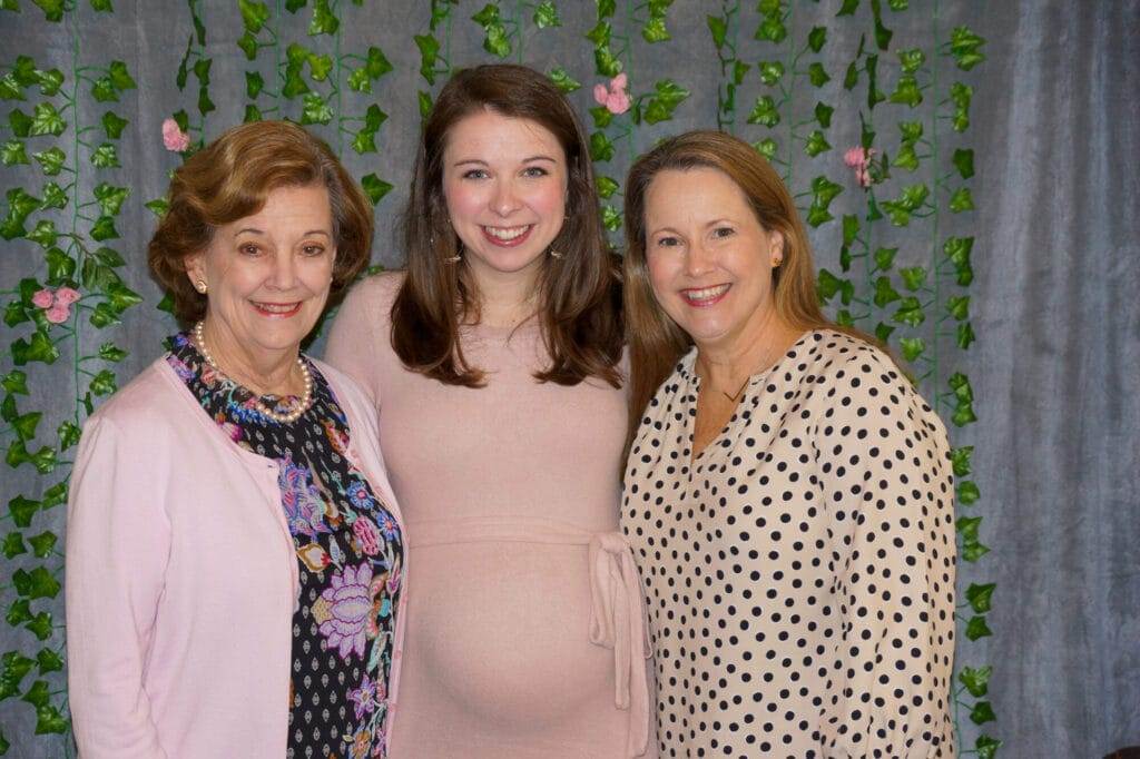 three women in front of ivy photo backdrop wall