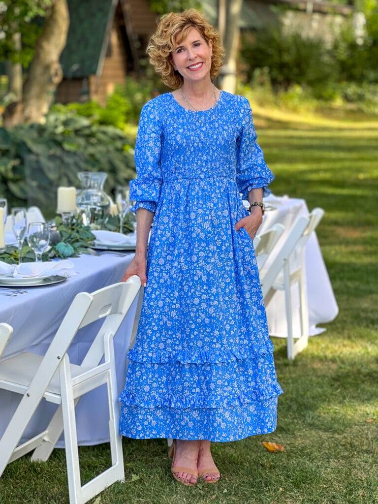 Woman wearing blue midi dress standing in a garden by a long table