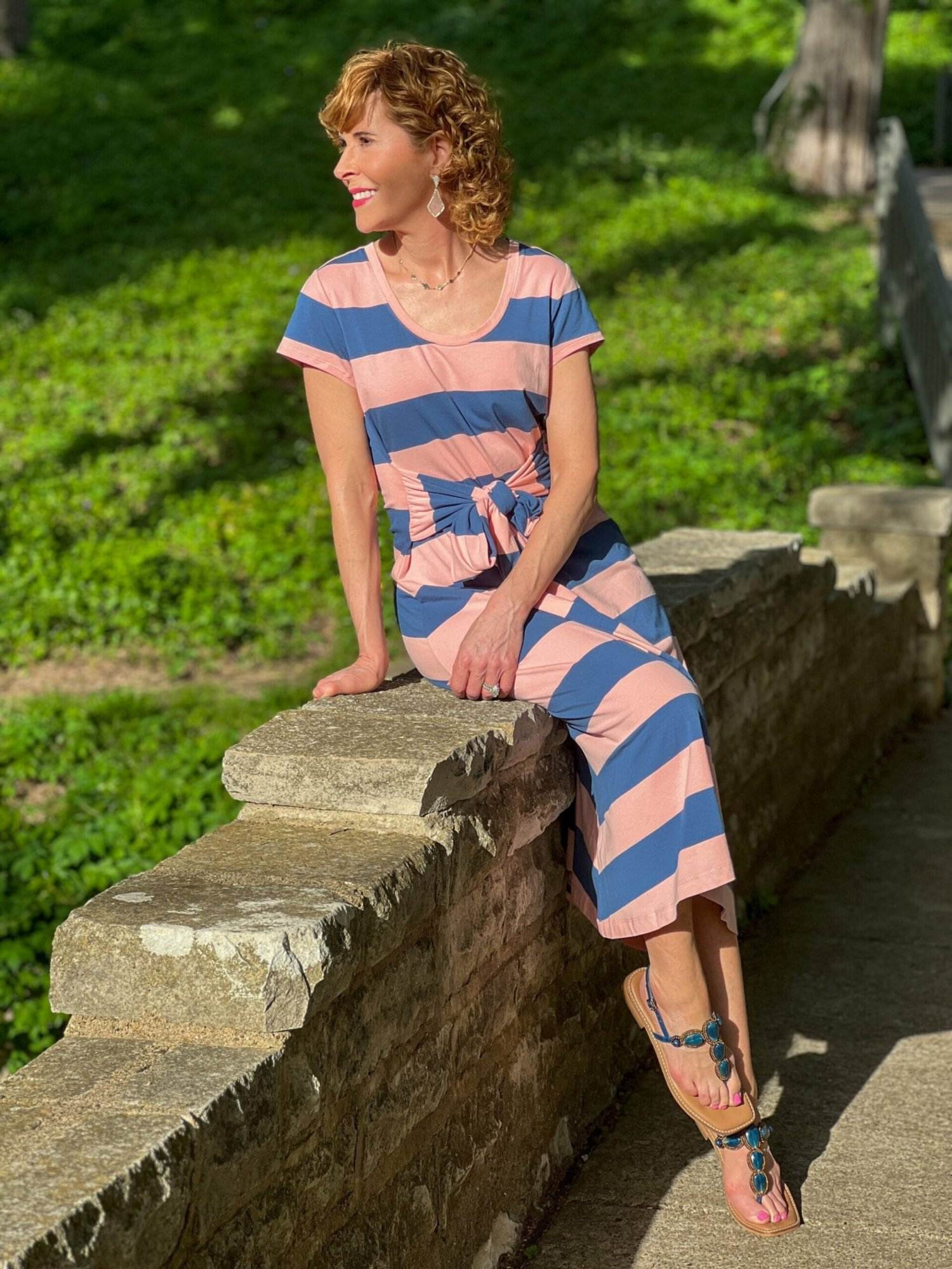 woman sitting on a bridge wearing coral and blue striped lands' end knit dress looking off to the distance