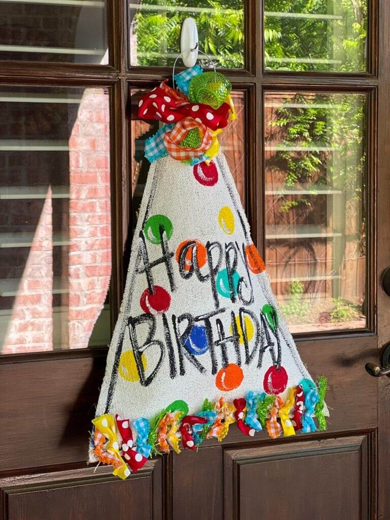 hand-painted burlap happy birhtday door hanger hanging on a back door