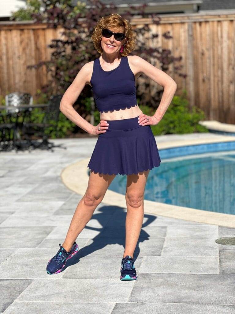 woman over 50 wearing navy blue scalloped workout set standing by a pool modeling amazon workout set in navy blue