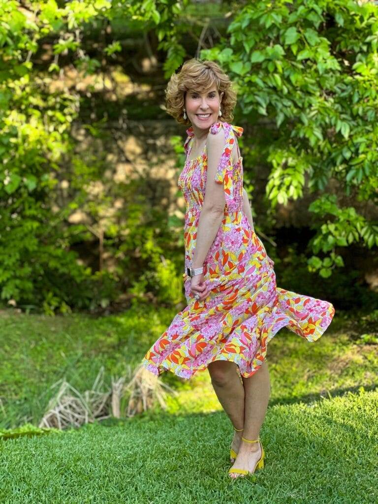 woman wearing colorful smocked top avara dress with shoulder ties twirling outside