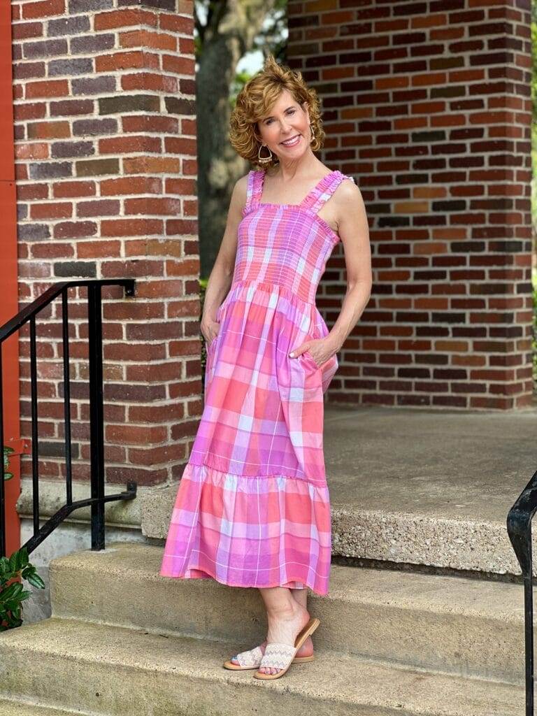 woman standing on stairs outdoors wearing Time and Tru Women's Smocked Midi Dress with Ruffle Straps from Walmart in pink madras plaid