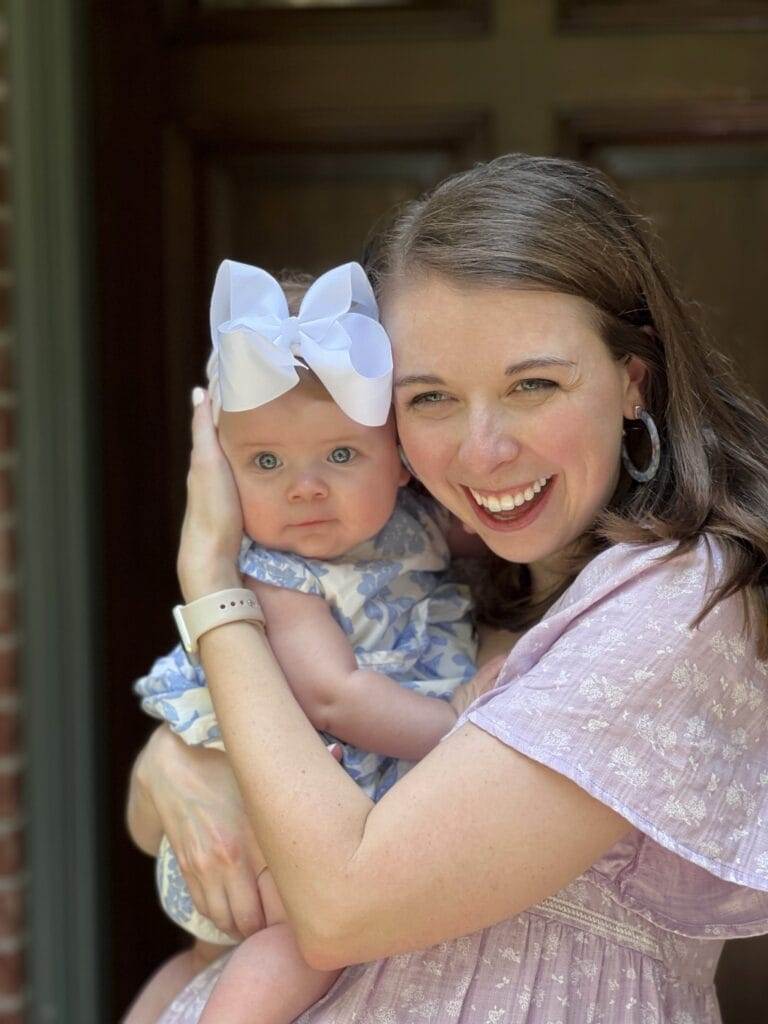 blue eyed mom and baby standing in front of a front door