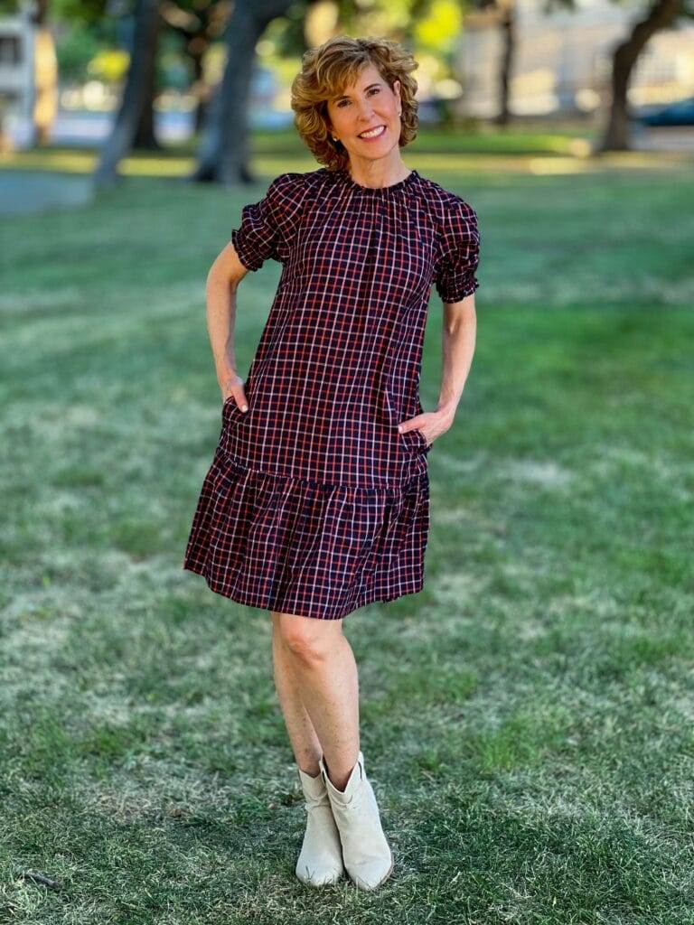 navy plaid shift dress on woman standing outdoors with off white slouch boots