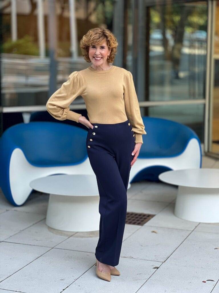 woman wearing talbots greenwich pants in navy with brass buttons and a gold top