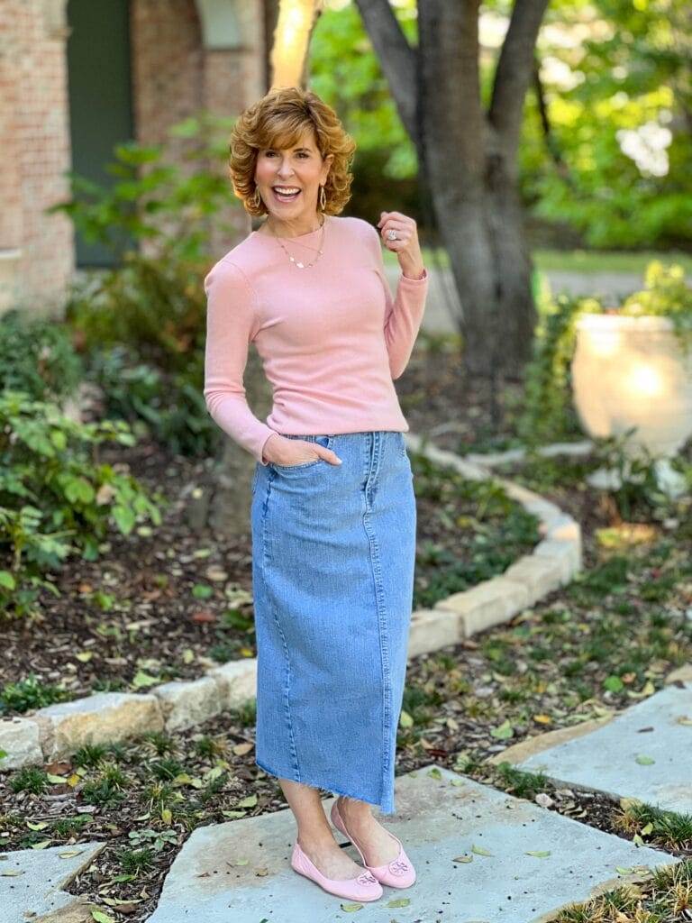 woman wearing pink crewneck sweater and pink ballet flats with long denim skirt