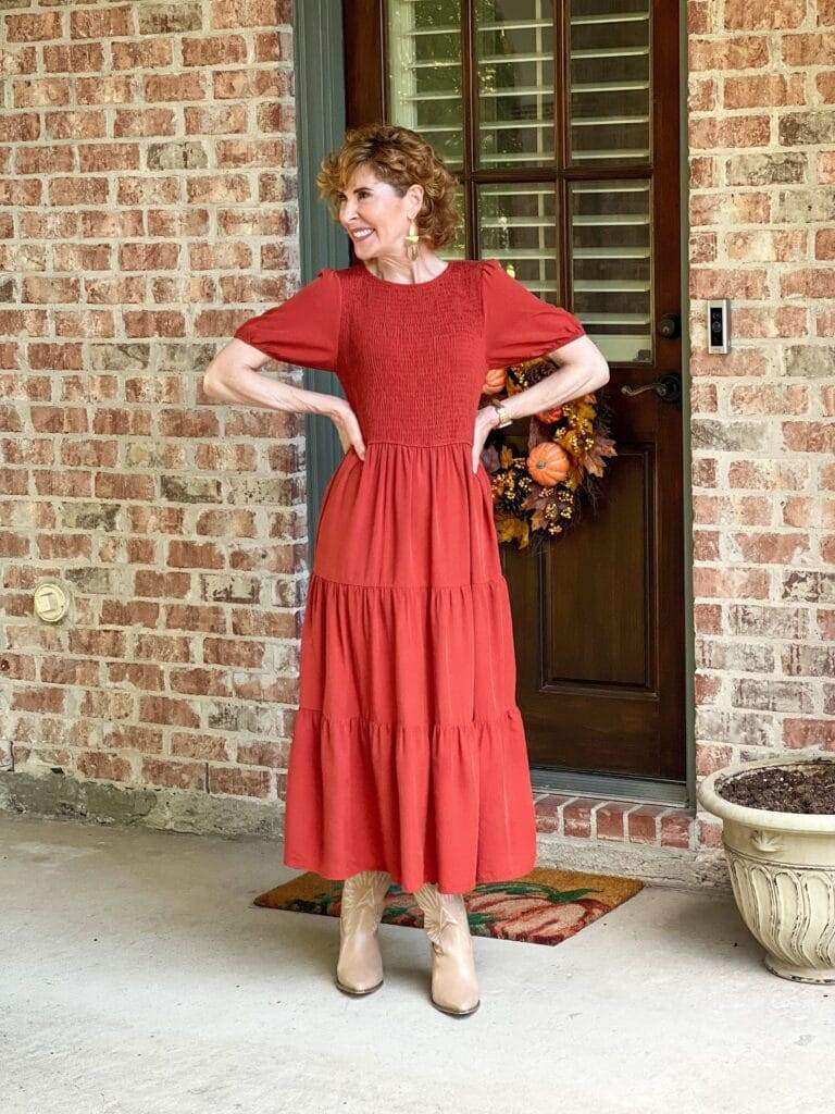 woman over 50 wearing rust amazon midi dress standing by back door looking to the side