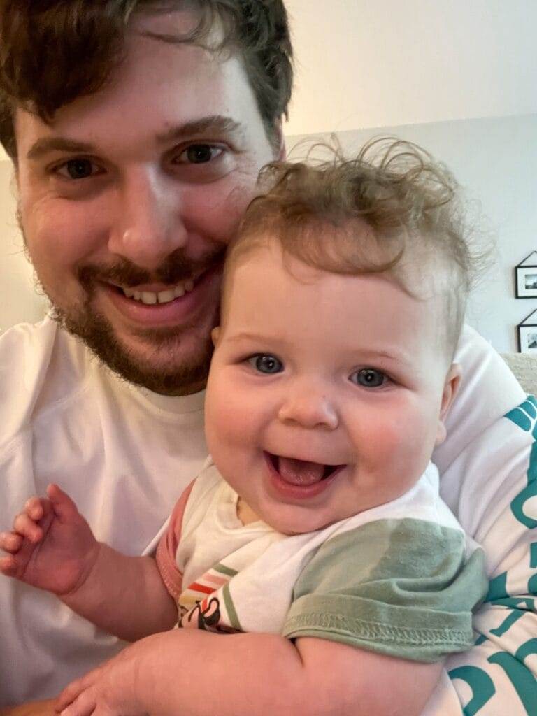 selfie of a young man with a beard and a baby