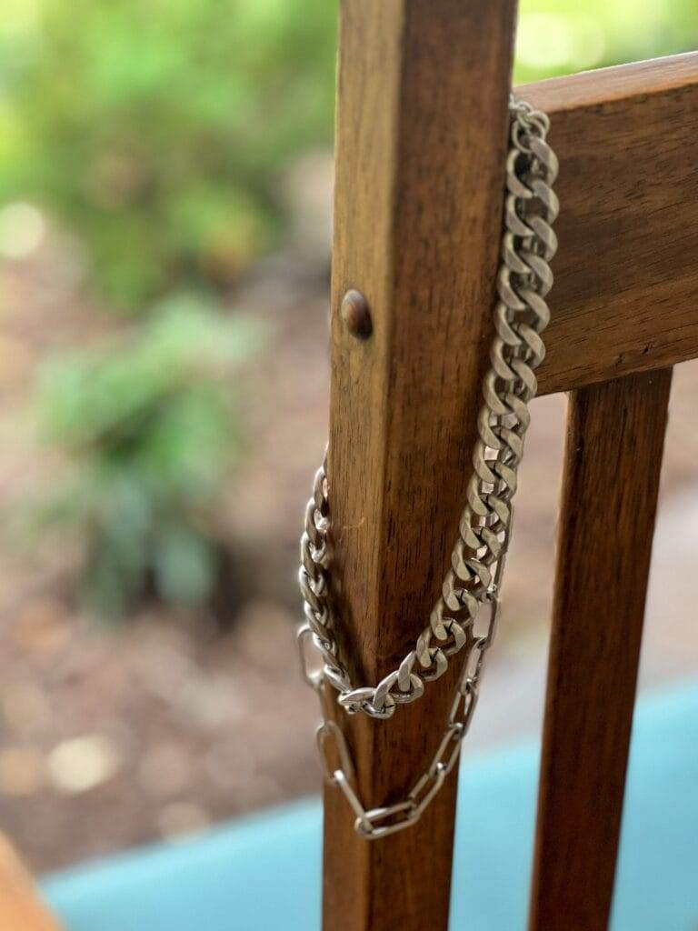 cabi id necklace in silver hanging over the side of a chair