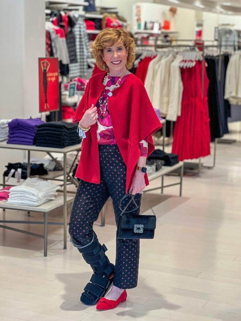 woman posing in a talbots store wearing a red cape over a floral sweater