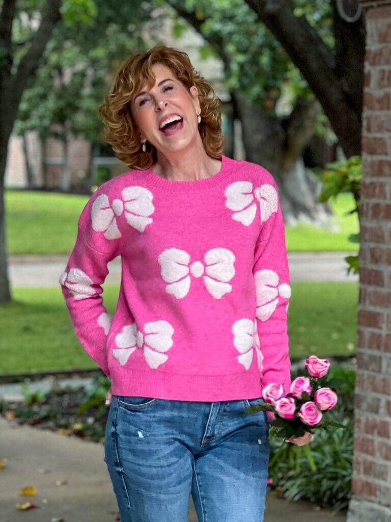 woman laughing wearing pink and white bow sweater