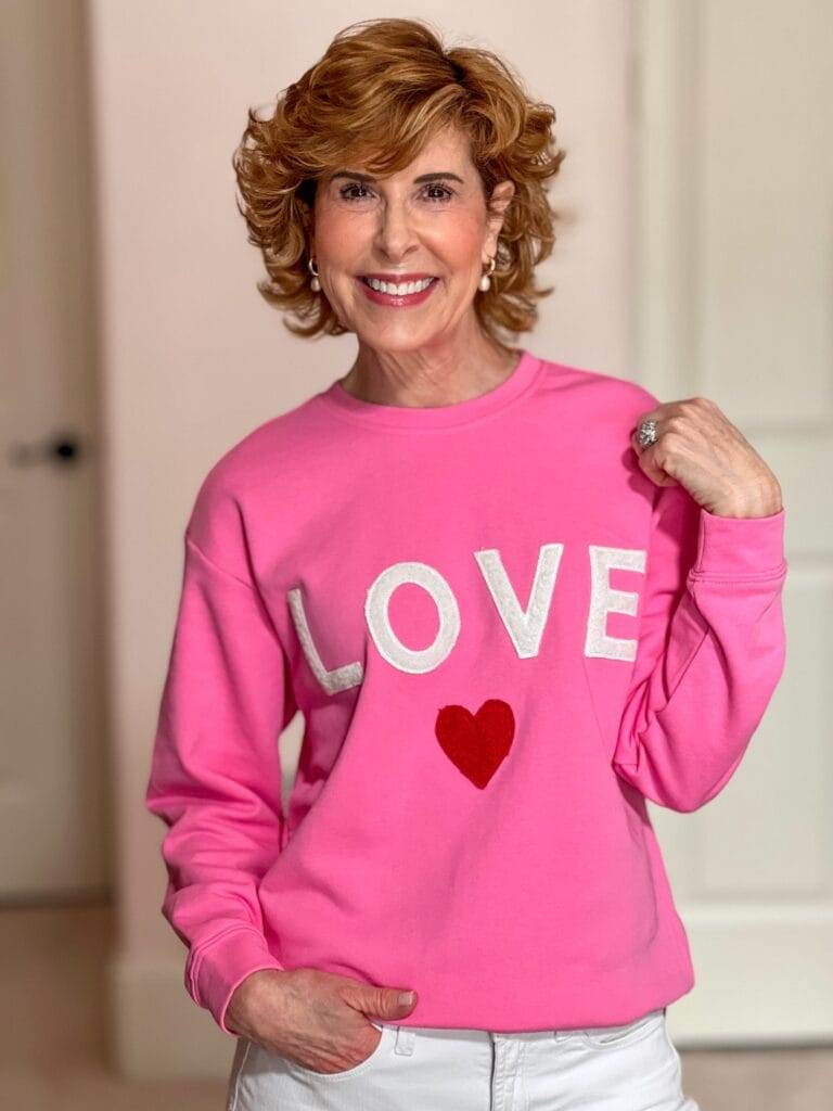 Woman over 50 wearing pink Avara LOVE sweatshirt.