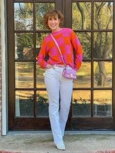 woman wearing pink and orange sweater from avara standing in front of french doors