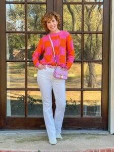 woman wearing pink and orange sweater from avara standing in front of french doors