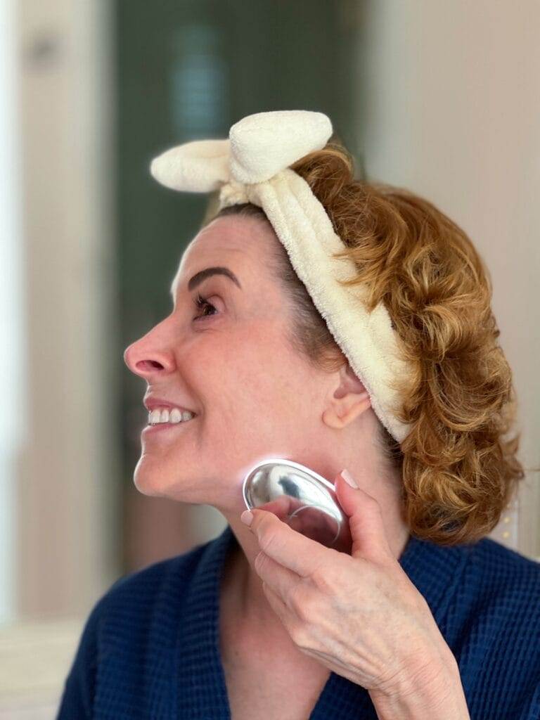 woman over 50 with her hair in a bow headband and wearing a robe using Ziip Halo microcurrent and nanocurrent device