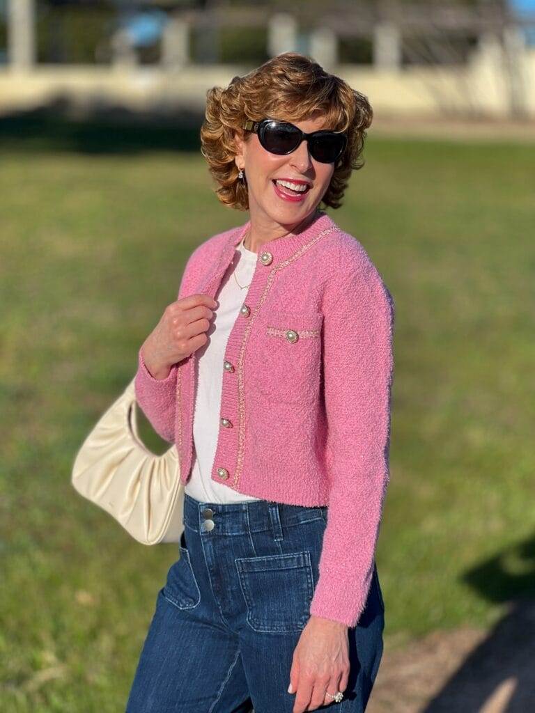 woman carrying white handbag and wearing pink jacket in park