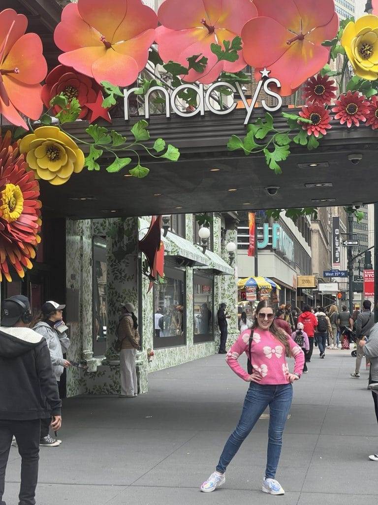 girl in pink sweater standing in front of macy's nyc