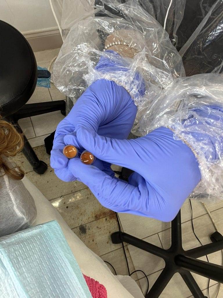 hands with blue latex gloves holding pigments to be used for eyebrow color correction