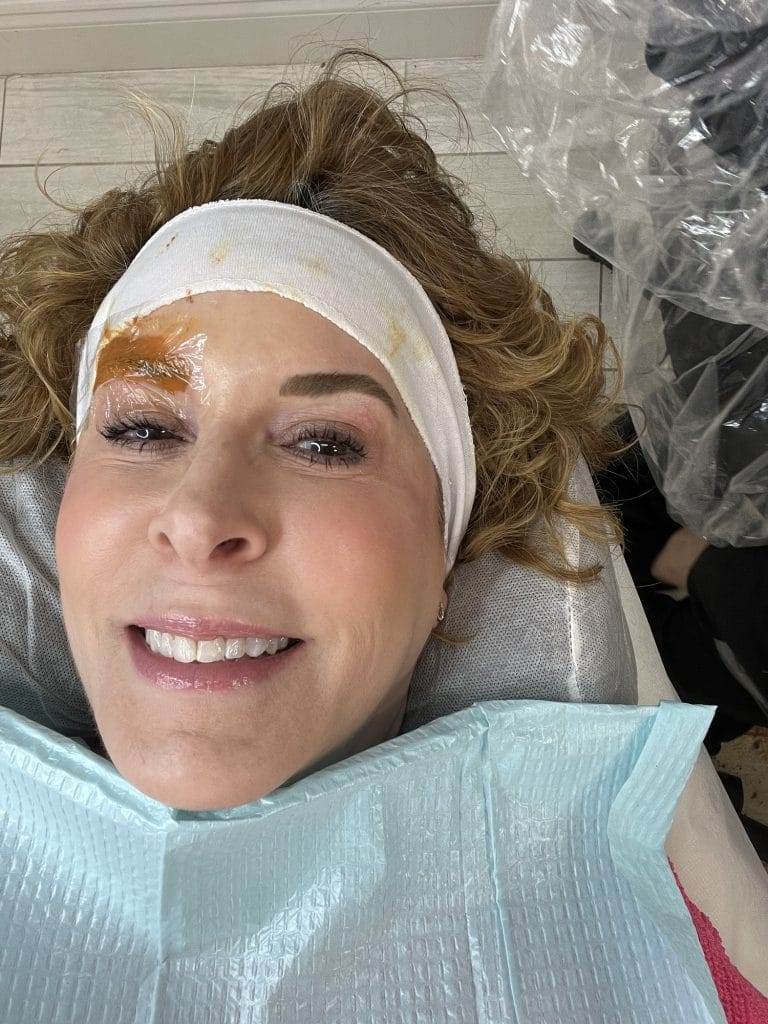 woman wearing white headband during eyebrow color correction procedure