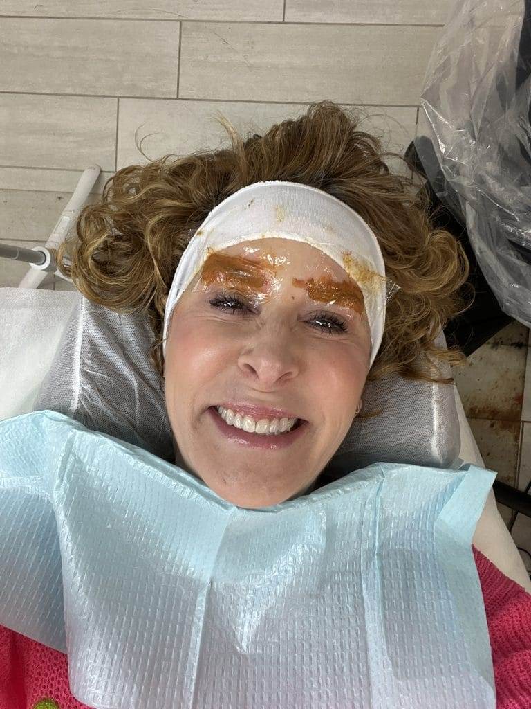 woman wearing white headband during eyebrow color correction procedure