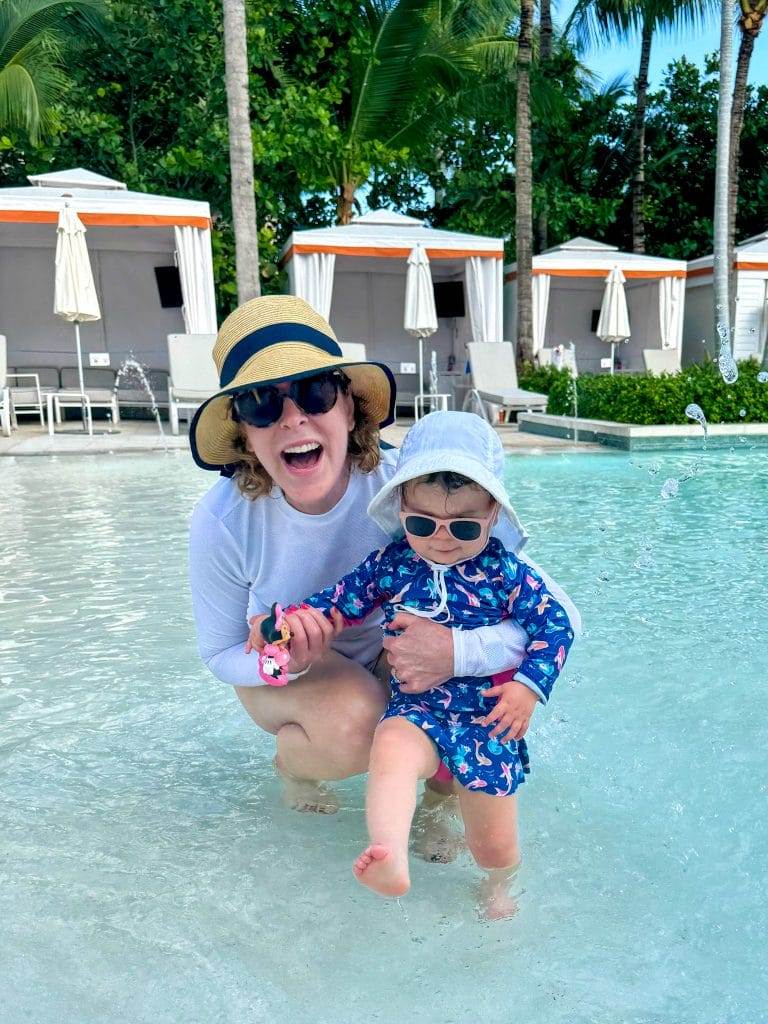 woman over 50 playing with baby in the shallow end of a pool