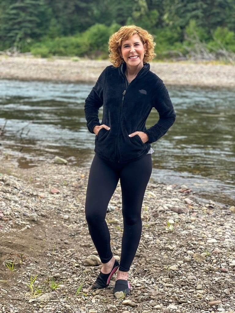 woman in all black workout gear next to a river in montana