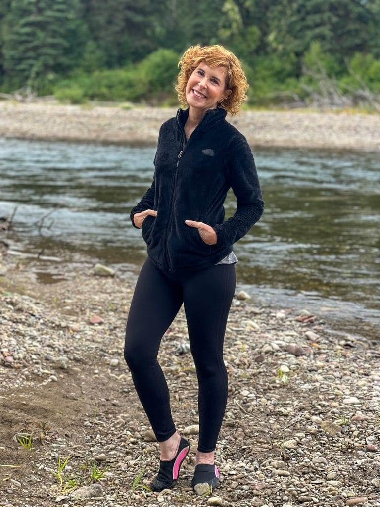 woman in all black workout gear next to a river in montana