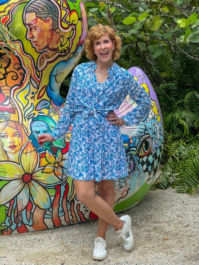 woman wearing lilly pulitzer Jilly Smocked Dress and Sea View Linen Button Down Top in front of a colorful grafitti rock