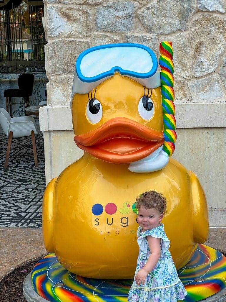 baby with curly hair in front of sugar factory ducky