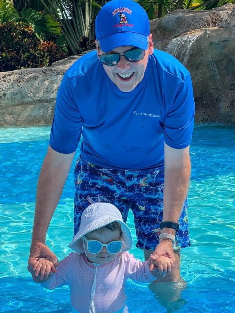 man dresssd in blue and baby playing in a pool