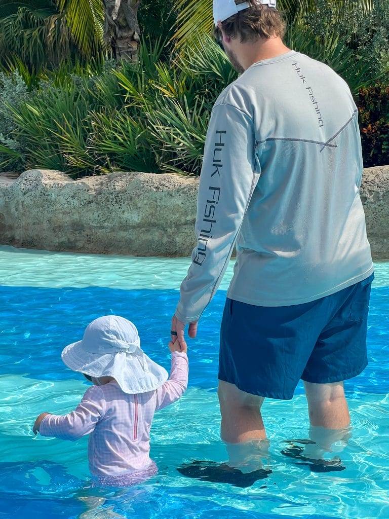 man and his baby daughter walking in a pool