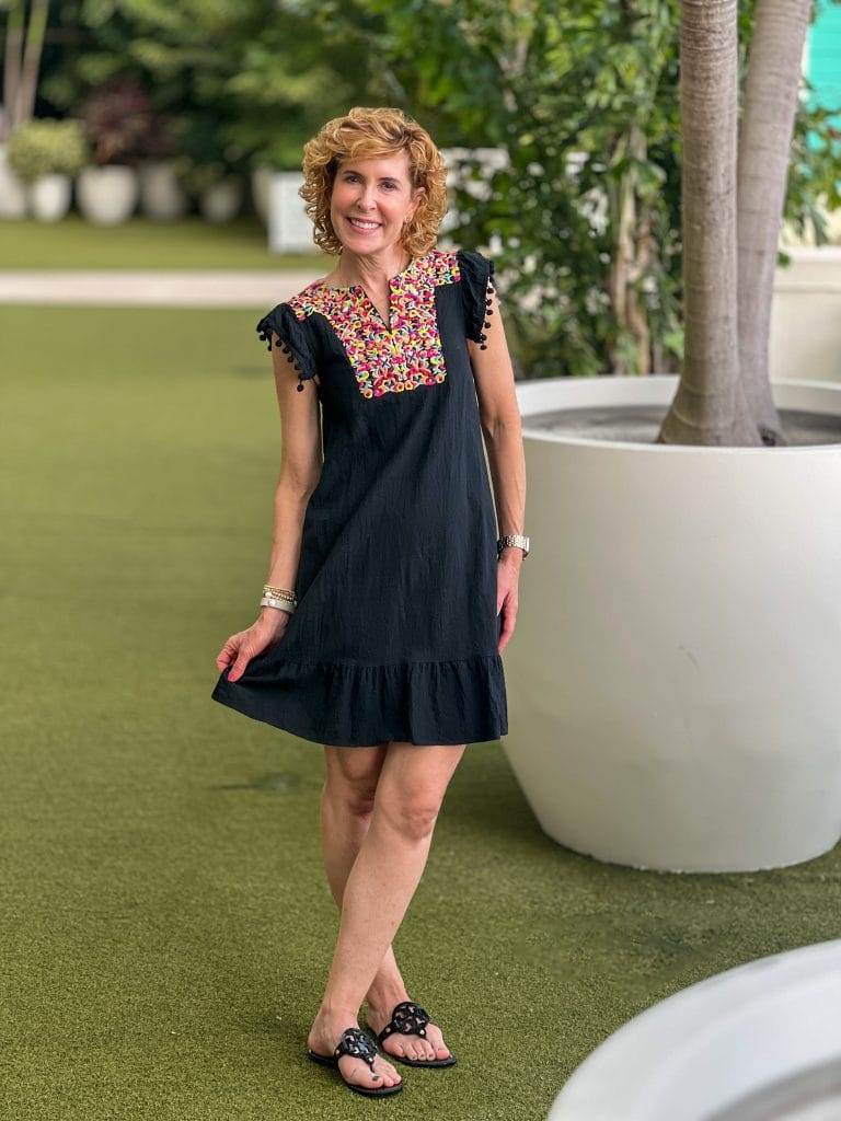 woman wearing colorful black linen dress and black sandals standing outside