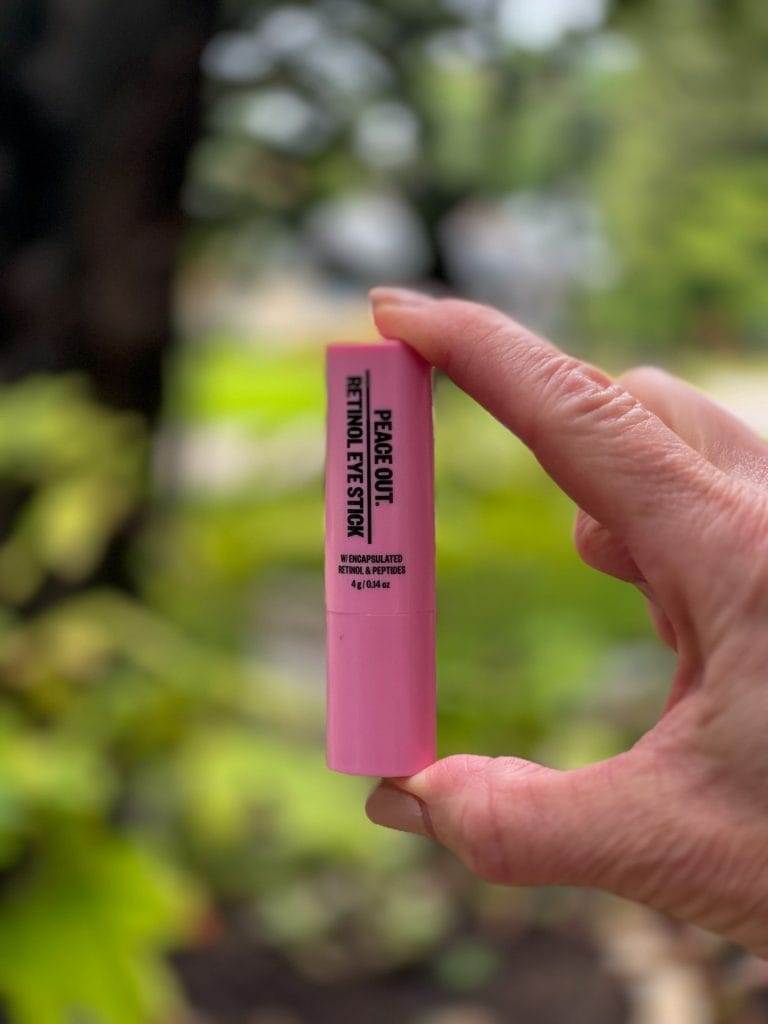 woman's hand holding peace out retinol eye stick