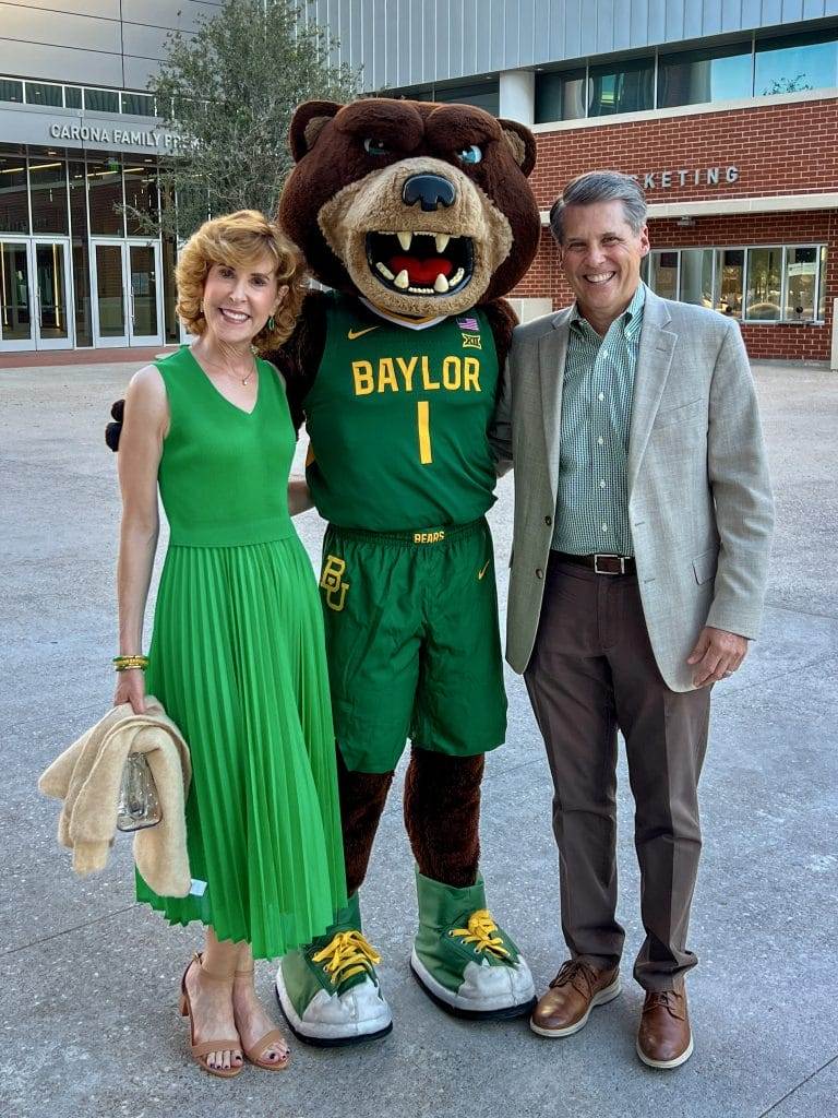 woman and man standing with bruiser the baylor mascot