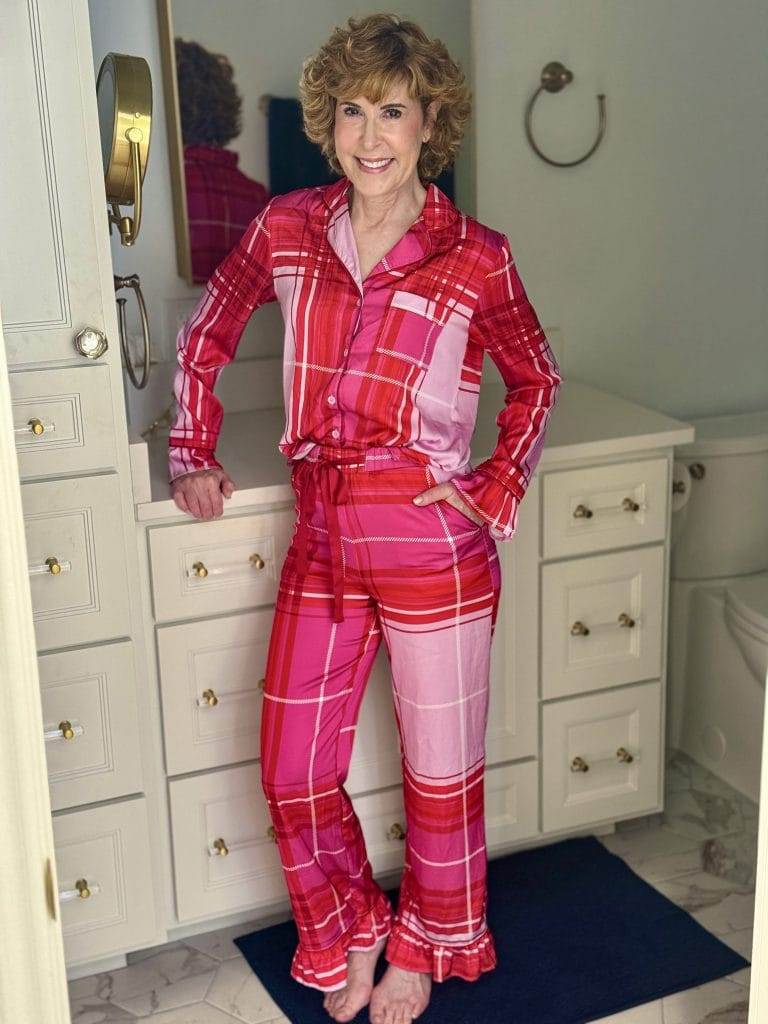 woman standing in a bathroom with red and pink plaid holiday pajamas that are long sleeve and long pants